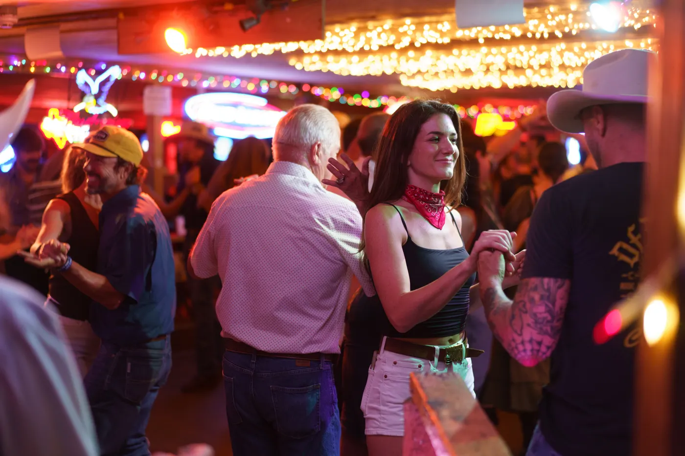 Couples two-stepping under the neon at the Broken Spoke